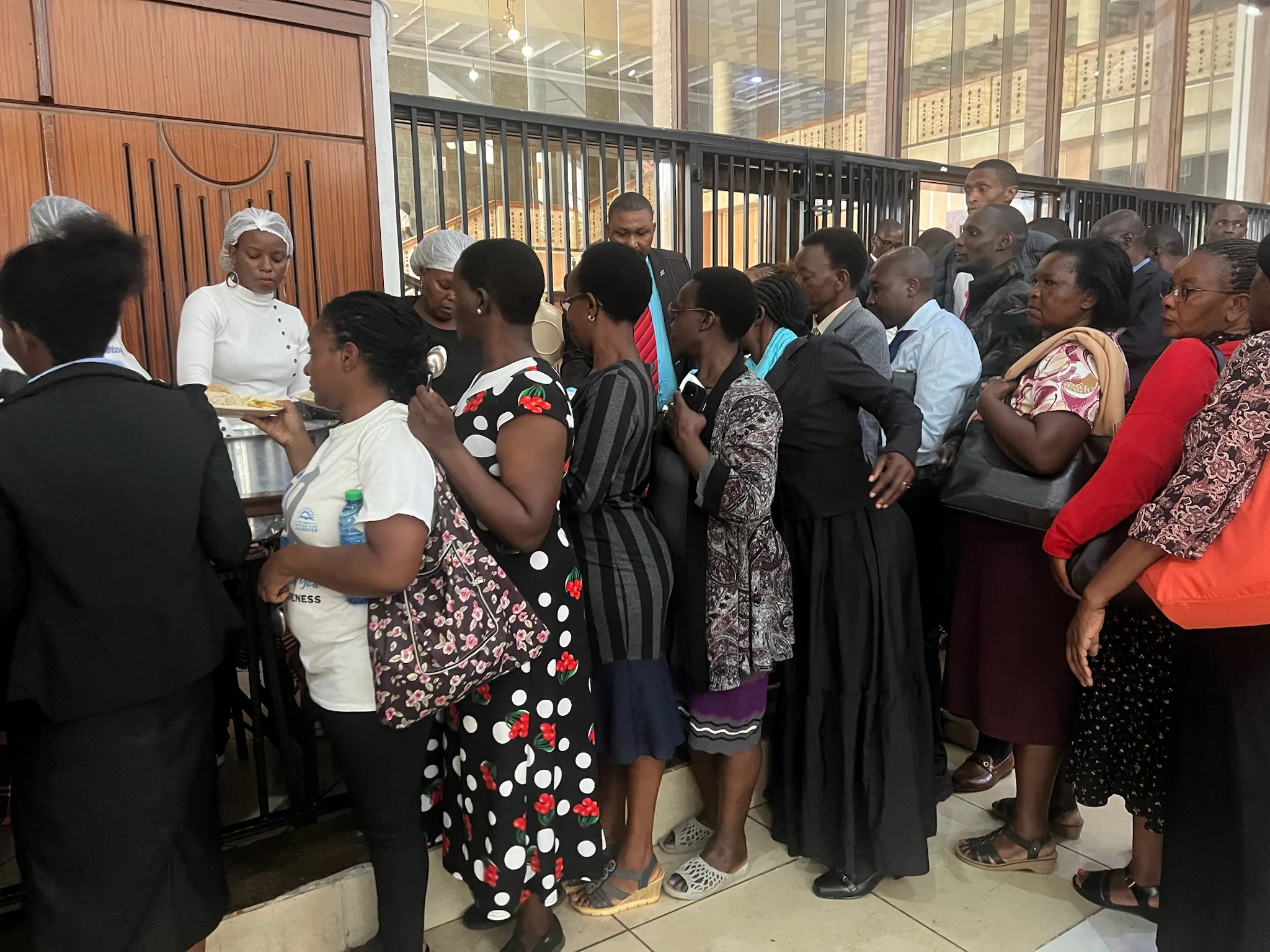 Conference attendees wait in line while a meal is served from a table inside the venue.