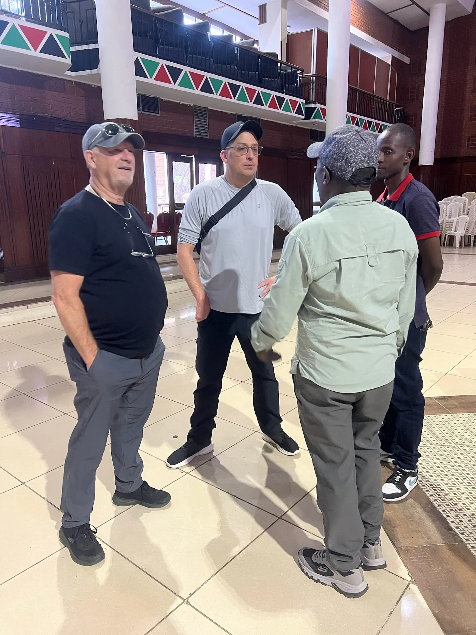 Michael Young and Don Kremer stand with local ministry leaders while discussing conference preparations inside Charter Hall.